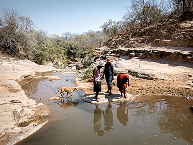 Die Freundinnen Beauty Nyathi (45), Gracious Mujuma (42) und Sihle Hahlani (31) am Fluss Chiurayi. Hier haben sie früher Wasser geholt. Durch MeDRAs Arbeit (BfdW-Partnerorganisation) hat sich ihr Leben sehr verbessert. Sie lernen und unterstützen sich gegenseitig.