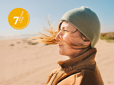 Das Motiv der Fastenaktion 2025 zeigt eine Frau, die in warmer Kleidung im Wind an einem Strand steht. Das Motiv der Fastenaktion 2025 zeigt eine Frau, die in warmer Kleidung im Wind an einem Strand steht.