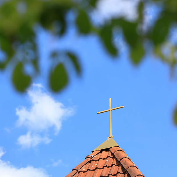 Kirchturm mit Kreuz vor blauem Himmel mit Wolken Kirchturm mit Kreuz vor blauem Himmel mit Wolken