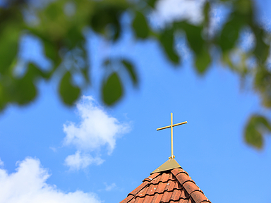 Kirchturm mit Kreuz vor blauem Himmel mit Wolken Kirchturm mit Kreuz vor blauem Himmel mit Wolken