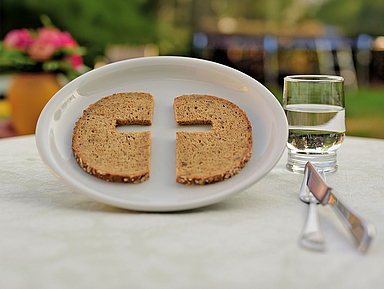 Unser Foto zeigt ein Symbolbild zur Fastenzeit mit Teller, Brot und Wasser