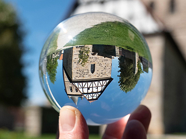 Unser Foto zeigt die Evangelische Kirche in Großenritte durch eine Glaskugel betrachtet. Kirchengebäude neu gedacht: Mit der Initiative sollen im Dialog Ideen entstehen, Kirchenräume über den gottesdienstlichen Bereich hinaus zu nutzen und als Orte für Begegnung, Kultur und Gemeinschaft zu öffnen. Unser Foto zeigt die Evangelische Kirche in Großenritte durch eine Glaskugel betrachtet. Die Kirche stammt aus dem 16. Jahrhundert.