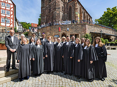 Gruppenfoto vor der Homberger Stadtkirche Die 10 frisch ordinierten Pfarrerinnen und Pfarrer mit (1.R.v.l.): Pfarrerin Jana Koch-Zeißig , Studienleiterin Johanna Fischer, Studienseminardirektorin Dr. Regina Sommer, (2.R.v.l.): Kirchenvorsteher Dr. Jürgen Helm, Pfarrerin Anke Zimmermann (Homberg/Efze), Studienleiter Thomas Hof und Bischöfin Dr. Beate Hofmann vor der Homberger Stadtkirche